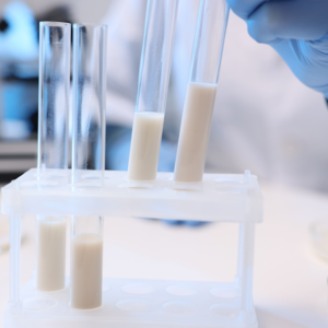 Photograph of test tubes with milky solution in rack and gloved hand in laboratory
