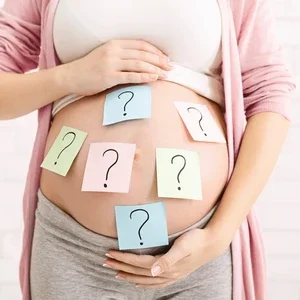 Photograph of pregnant torso cradled by hands with blue sticky notes showing question marks
