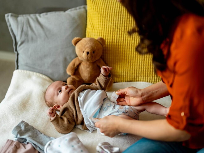 Mãe a mudar a fralda do bebé Mãe a mudar a fralda do bebé
