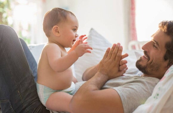 Pai a brincar com bebé no sofá Pai a brincar com bebé no sofá