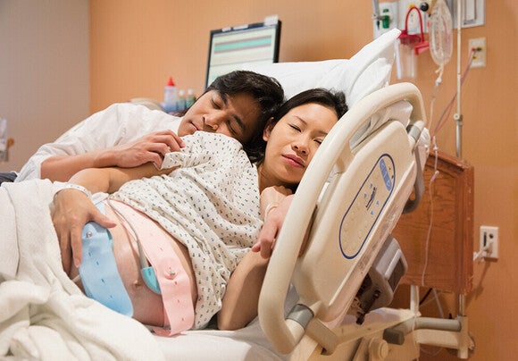 Hospital photograph: woman in a hospital bed hugging supportively.